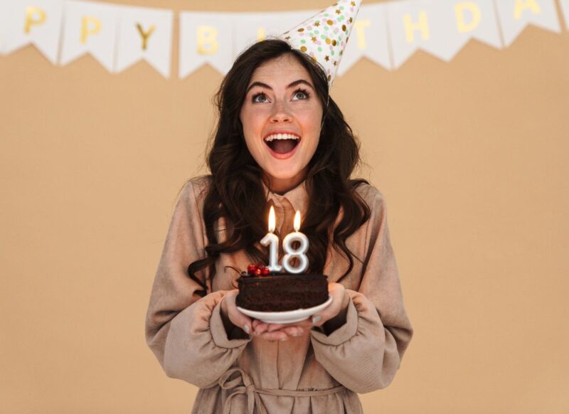 devojka u haljini sa tortom u ruci i svećicama za 18 rođendan